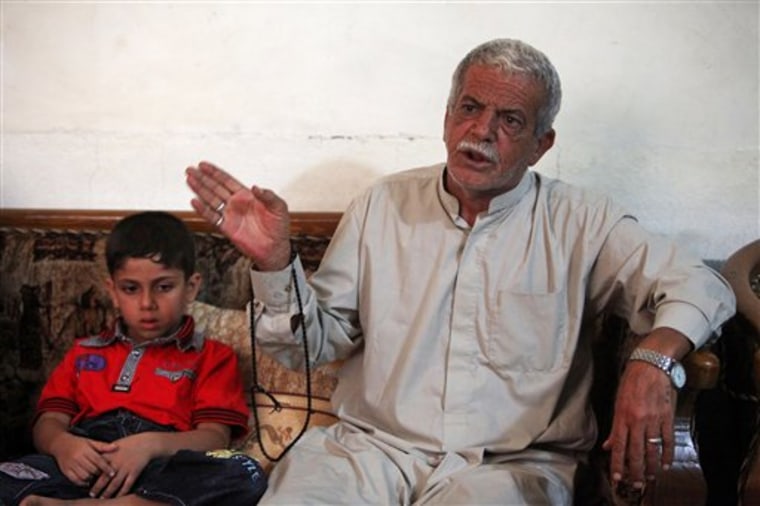 Mohammed Ali, 65, right, grandfather of  10-year-old Tabark Thaer, not shown, speaks at his home in the holy city of Karbala, 80 kilometers (50 miles) south of Baghdad, Iraq, Thursday Sept. 15, 2011. Tabarak is a survivor of a hijacking Monday Sept. 12, 2011 in Iraq's Sunni-dominated western Anbar province that left 22 Shiite pilgrims dead. The passengers were from  Karbala and were headed to the Sayyida Zainab shrine in Damascus, Syria. The boy at left is unidentified. (AP PhotoAhmed al-Husseini)